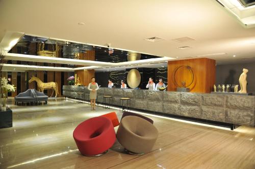 a lobby with red chairs and a bar with people at 重庆江北观音桥高悦酒店地铁站店KaoYu Hotel in Chongqing