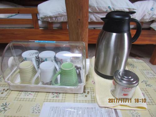 un recipiente lleno de tazas y platos y una cafetera en Daichan House, en Yakushima