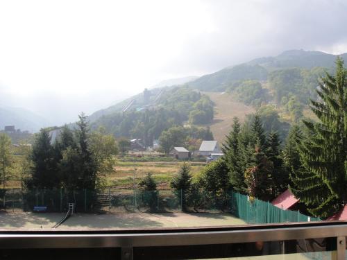 a view of a mountain with a fence and trees at Rosenheim Hakuba in Hakuba