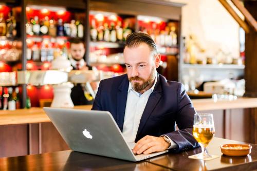 a man sitting at a table using a laptop computer at Parkhotel Krone in Bensheim