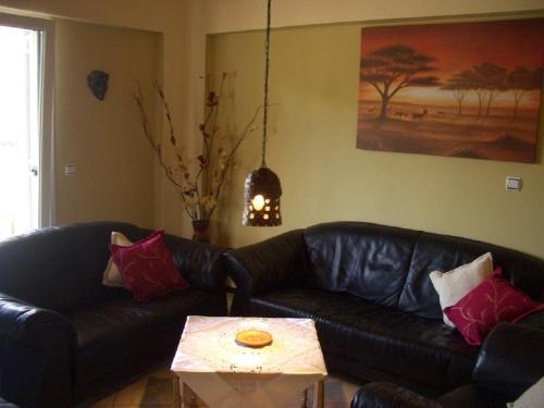 a living room with a black leather couch and a coffee table at Aspri Villa in Ammoudia