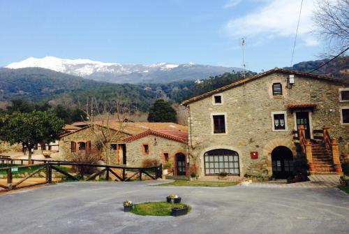 a large stone building with mountains in the background at Can Marc in Sant Esteve de Palautordera