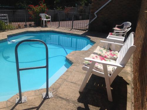 a pair of chairs sitting next to a swimming pool at Blue Fern of Knysna in Knysna
