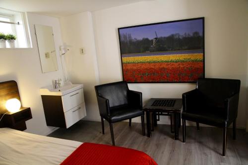 a bedroom with two chairs and a painting on the wall at budget rooms Doppenberg in Zandvoort
