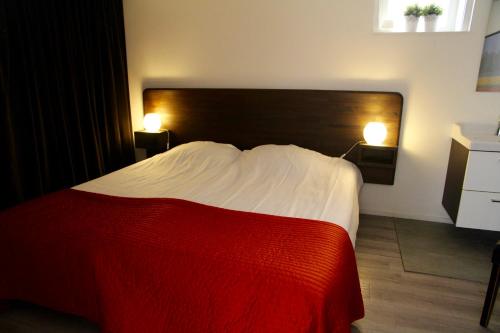 a bedroom with a red and white bed with two lamps at budget rooms Doppenberg in Zandvoort