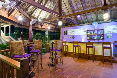 un restaurant avec un bar avec des tabourets violets dans l'établissement Riviera Hotel & Resort Kep, à Kep