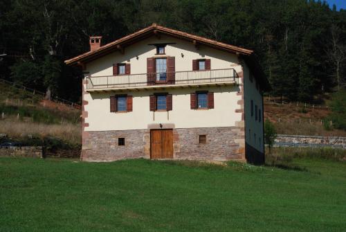 a large building with a balcony on top of a field at Casa rural Lakoizketa in Legasa