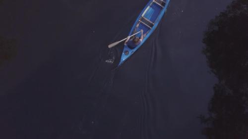 a man in a blue boat in the water at Stilleben Hotell in Åmot