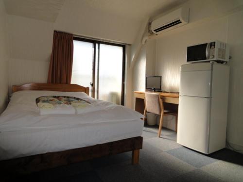 1 dormitorio con cama, escritorio y nevera en Soho Asakusa Hotel, en Tokio