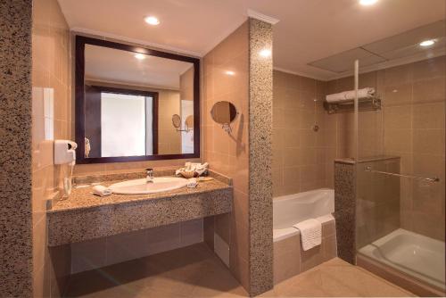 a bathroom with a sink and a tub and a mirror at Stella Gardens Resort & Spa, Makadi Bay in Hurghada