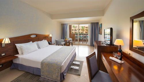 een hotelkamer met een groot bed en een bureau bij Stella Gardens Resort & Spa, Makadi Bay in Hurghada