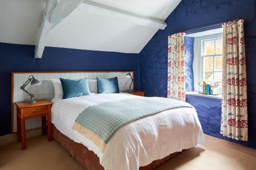 a blue bedroom with a bed and a window at Y Meirionnydd Townhouse in Dolgellau