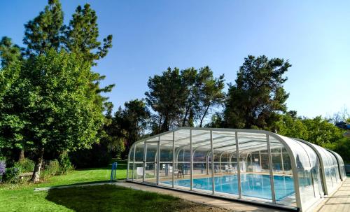 a glass greenhouse next to a swimming pool at Nofey Habashan in Lahavot HaBashan