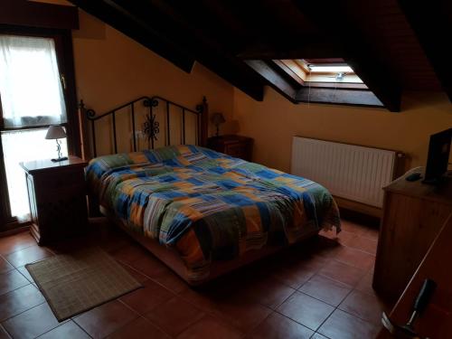 a bedroom with a bed with a colorful comforter at nueva el bosquin in Nueva de Llanes