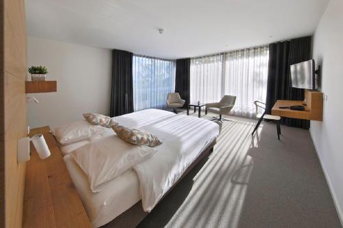 a bedroom with a bed and a desk and a television at Hotel Berghoeve in Epen