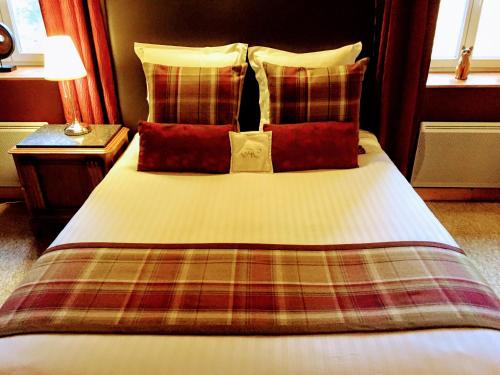 a bed with red pillows and a plaid blanket at Chabanettes Hotel & Spa in Auzelles