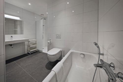 a bathroom with a tub and a toilet and a sink at Hotel Berghoeve in Epen