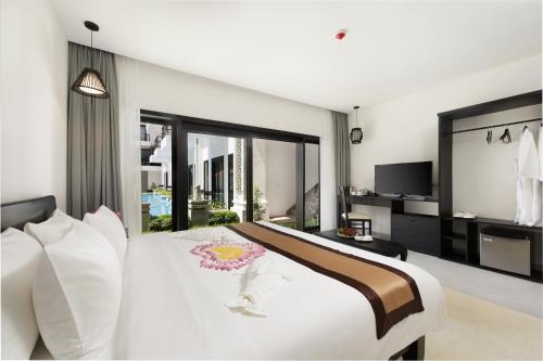 a bedroom with a large white bed and a tv at Aroma Angkor Boutique Hotel in Siem Reap