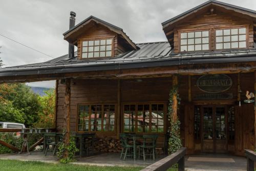 a log cabin with tables and chairs outside of it at Hotel El Barranco in Futaleufú
