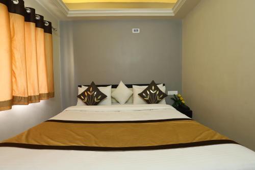 a bedroom with a large bed with orange curtains at Hotel Loyal Residency in Jamnagar