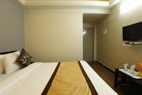 a hotel room with a bed and a flat screen tv at Hotel Loyal Residency in Jamnagar
