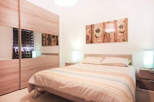 a white bedroom with a large bed and a window at Mellieha sea and land view apartment in Mellieħa