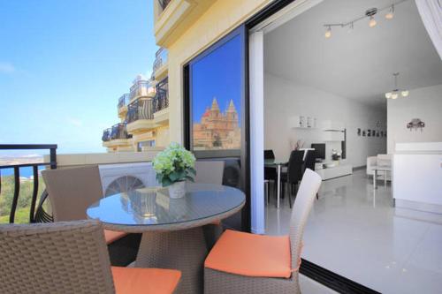 a dining room with a glass table and chairs at Mellieha sea and land view apartment in Mellieħa
