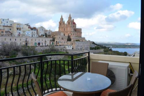 a table and chairs on a balcony with a view of a building at Mellieha sea and land view apartment in Mellieħa