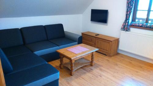 a living room with a blue couch and a table at Pension Polubný 922 in Kořenov
