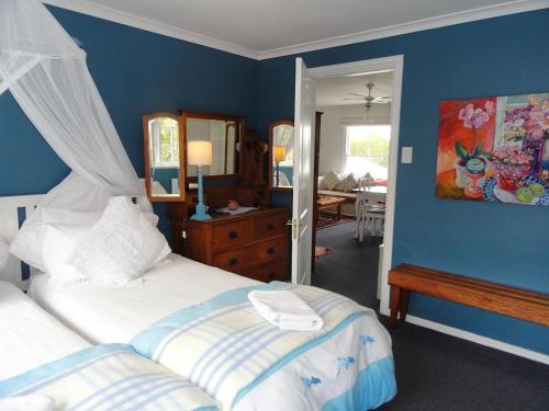 a bedroom with two beds and a blue wall at Eastbury Cottage in Hermanus