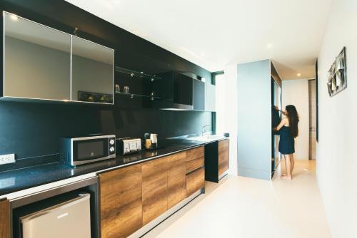 a woman standing in a kitchen with a microwave at Searocco Phuket in Patong Beach