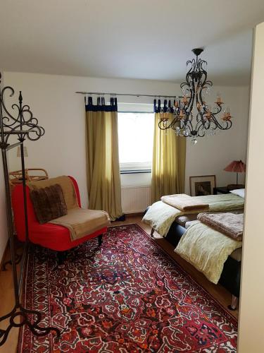 a bedroom with two beds and a chair and a chandelier at Jagd trifft Moderne & Boutique Jardin Ferienhaus in Annaberg im Lammertal