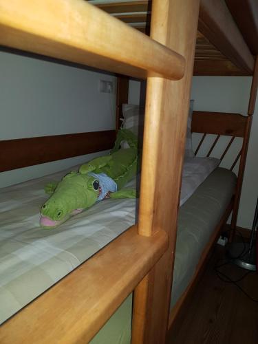 a green stuffed lizard laying on a bunk bed at Jagd trifft Moderne & Boutique Jardin Ferienhaus in Annaberg im Lammertal
