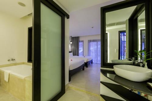a bathroom with a tub and a sink and a bed at Aroma Angkor Boutique Hotel in Siem Reap