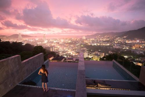 a woman standing on top of a building looking at a city at Searocco Phuket in Patong Beach