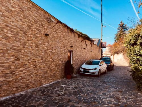 two cars parked next to a brick wall at Atrium Panzio in Esztergom