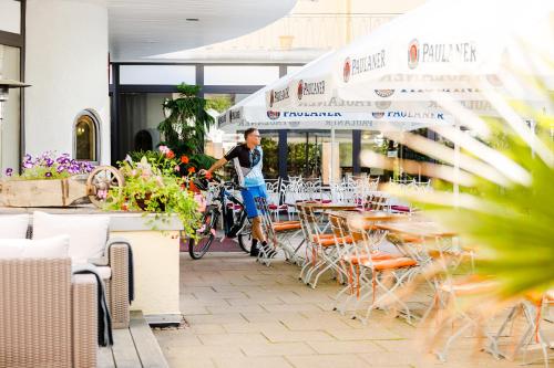 a man on a bike standing next to tables and chairs at Parkhotel Krone in Bensheim