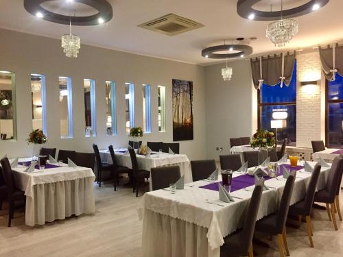 een eetkamer met tafels en stoelen met wit linnengoed bij Hotel Pod Jeleniem in Tuchola