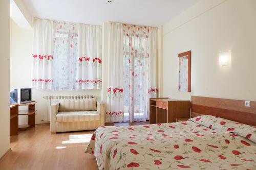 a bedroom with a bed and a chair and curtains at Family Hotel Gorski Kut in Rilski Manastir