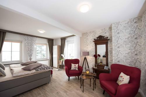 a bedroom with a bed and two red chairs at Sonnenhof Plauen in Plauen