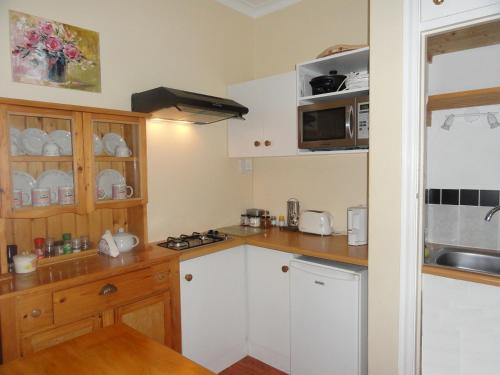 a kitchen with white cabinets and a counter top at Eastbury Cottage in Hermanus