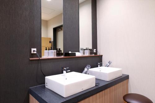 a bathroom with two white sinks and a mirror at Almont Hotel Sendai in Sendai