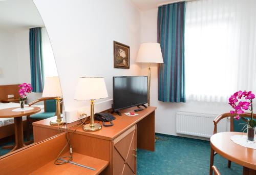 a hotel room with a desk with a television at Hotel Stadt Waren in Waren