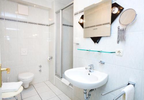 a white bathroom with a sink and a toilet at Hotel Stadt Waren in Waren