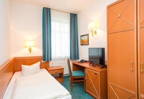 a hotel room with a bed and a desk at Hotel Stadt Waren in Waren