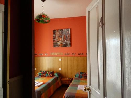 two beds in a room with orange walls at Pension Plaza in Quinto