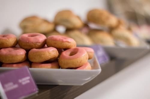 a tray of pink donuts on a counter with other pastries at LV Hoteles Boutique in Viña del Mar