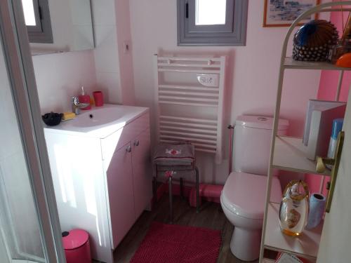 Baño de color rosa con aseo y lavamanos en La Vie Au Roze, en Quéven