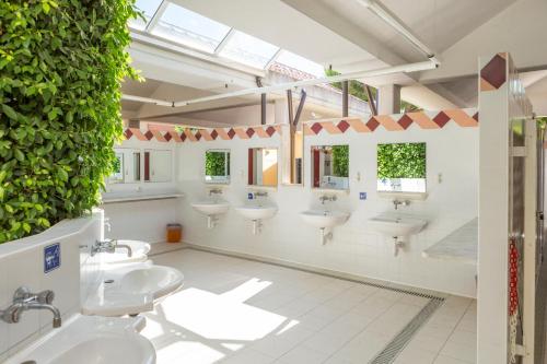 a bathroom with four sinks and a green wall at Riva Nuova Camping Village in Martinsicuro
