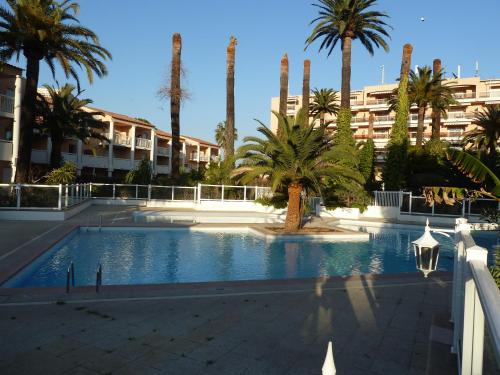 une piscine avec des palmiers dans un complexe hôtelier dans l'établissement App T2 cozy Proche de la Mer, au Golfe-Juan